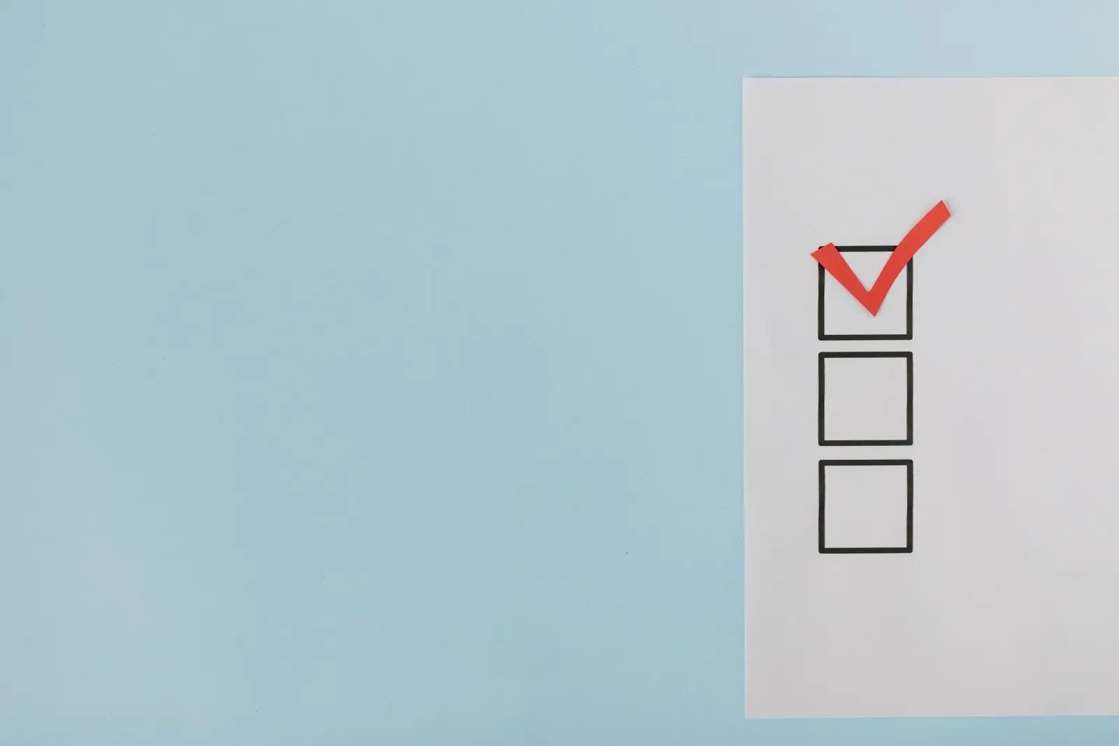 A minimalist checklist with a red checkmark on a blue background, providing ample copy space.